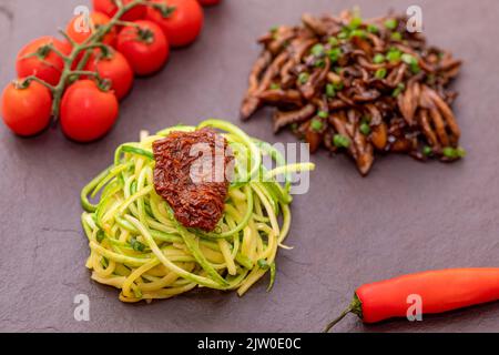 Zucchini-Spaghetti mit getrockneten und getrockneten Tomaten Stockfoto