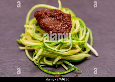 Zucchini-Spaghetti mit getrockneten und getrockneten Tomaten Stockfoto