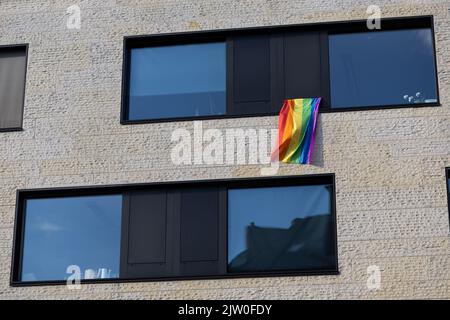 Westfalen, Deutschland. 02. September 2022. 02. September 2022, Nordrhein-Westfalen, Münster: Eine Regenbogenfahne als Symbol der LGBT-Bewegung hängt an einem Fenster. Auf dem Prinzipalmarkt demonstrieren Menschen gegen Gewalt gegen queere Menschen. Ein 25-jähriger Mann war bei einer Kundgebung am Christopher Street Day in Münster brutal geschlagen und schwer verletzt worden. Später erlag er seinen Verletzungen im Krankenhaus. Der Täter wurde noch nicht identifiziert. Foto: Friso Gentsch/dpa Kredit: dpa picture Alliance/Alamy Live News Stockfoto