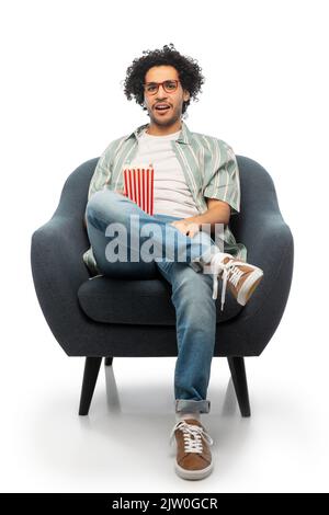 Mann mit Popcorn, der sich einen Film ansieht und auf einem Stuhl sitzt Stockfoto