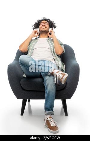 Mann in Kopfhörern, der im Stuhl Musik hört Stockfoto