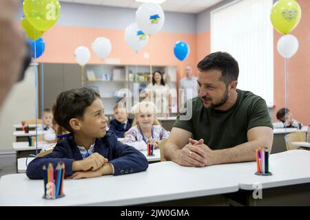 Irpin, Ukraine. 01. September 2022. Der ukrainische Präsident Wolodymyr Zelenskyy unterhielt sich am ersten Unterrichtstag an der Grundschule A. S. Makarenko am 1. September 2022 in Irpin, Ukraine, mit jungen Schülern. Die Schule wurde mit Hilfe von UNICEF nach der Zerstörung durch russische Angriffe im vergangenen März wieder aufgebaut. Quelle: Sarsenov Daniiar/Ukraine Presidency/Alamy Live News Stockfoto