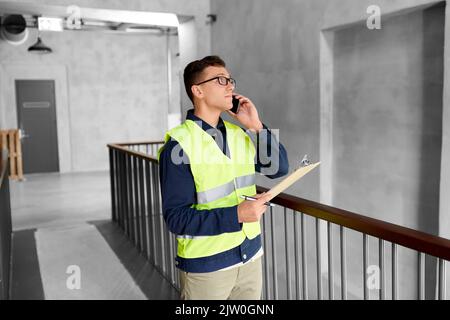 Männlicher Supervisor mit Anruf in der Zwischenablage am Telefon Stockfoto