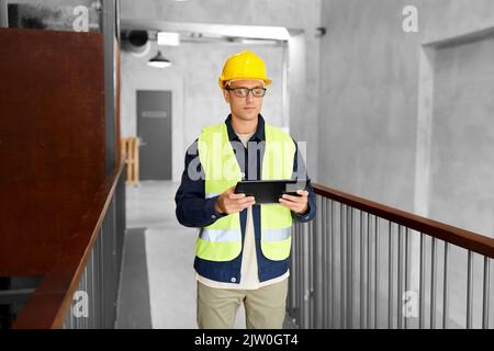 Arbeiter in Helm und Sicherheit Westen mit Tablet-pc Stockfoto