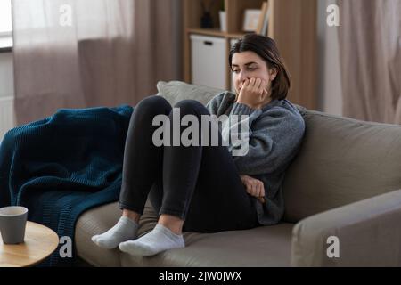 Gestresste Frau, die zu Hause auf dem Sofa sitzt Stockfoto