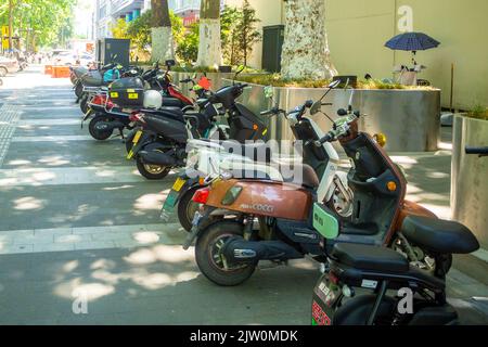 Eine Vielzahl von Motorroller oder Fahrräder sind auf einem Bürgersteig in der Innenstadt geparkt Stockfoto