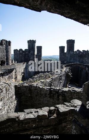 Blick nach Osten innerhalb von Conwy Castle über den Inner ward und Türme in Richtung Osten Barbican mit Llandudno Junction in der Ferne, North Wales Stockfoto