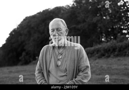 Alter Mann, der auf einem Feld steht und mit natürlichem Licht in die Kamera blickt. Stockfoto