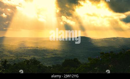 Sonnenlicht bricht durch Wolken in einem Feld. Stockfoto