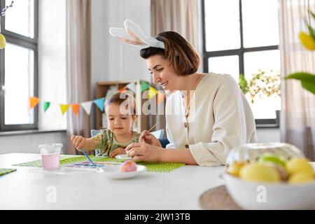 Mutter mit Kind färbt Ostereier zu Hause Stockfoto