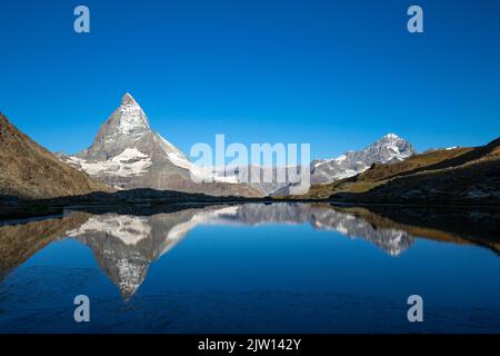 Das majestätische Matterhorn, der berühmteste Berg der Schweiz, spiegelt sich am frühen Morgen im Riffelsee in einer überwältigenden Landschaft wider. Stockfoto