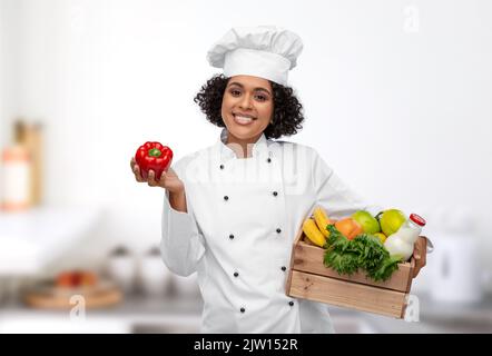 Weibliche Köchin mit Essen in Holzkiste in der Küche Stockfoto