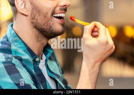 Nahaufnahme eines glücklichen Mannes, der Pommes frites isst Stockfoto