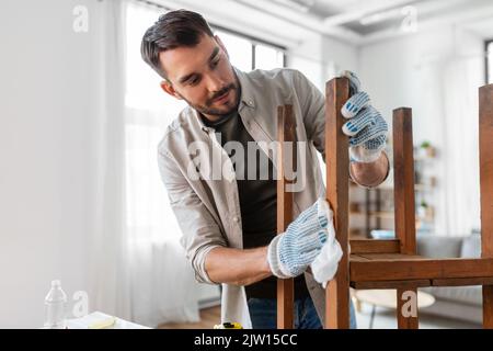 Mann, der die alte Tischoberfläche mit Gewebe reinigt Stockfoto