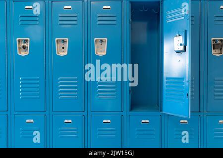 Schließfächer aus blauem Metall entlang eines unscheinbaren Flurs in einer typischen US High School. Keine identifizierbaren Informationen enthalten und niemand in der Halle. Stockfoto