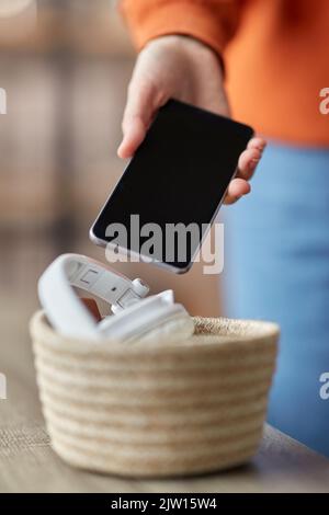 Hand hält Smartphone und Gadgets im Korb Stockfoto