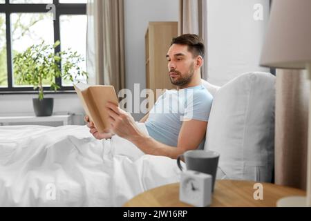 Mann lesen Buch im Bett zu Hause. Stockfoto