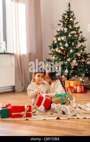 Mädchen küssen Bruder mit weihnachtsgeschenken zu Hause Stockfoto