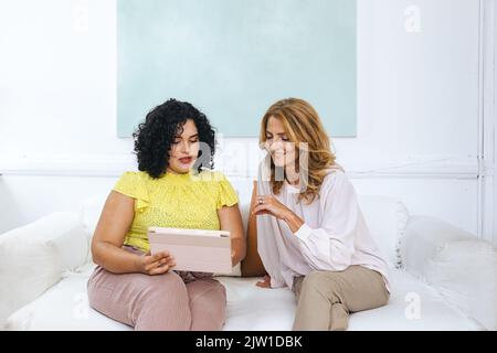 Kreative Geschäftsfrau erklärt Kollegen die Strategie über ein digitales Tablet im Büro Stockfoto