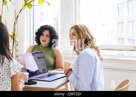 Reife Geschäftsfrau diskutiert Ideen mit weiblichen Kollegen im Kreativbüro Stockfoto