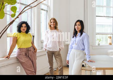 Porträt von lächelnden reifen Geschäftsfrauen inmitten von weiblichen Kollegen im Bürostudio Stockfoto
