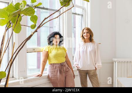 Porträt von selbstbewussten Geschäftskollegen am Fenster im Bürostudio Stockfoto