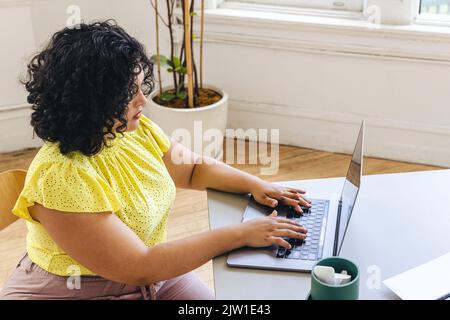 Aus dem hohen Blickwinkel sehen Sie, wie eine Unternehmerin während der Arbeit im Bürostudio auf dem Laptop tippt Stockfoto