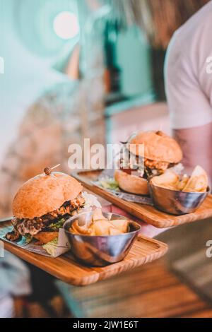 Kellner mit zwei Cheeseburgern und Pommes Stockfoto