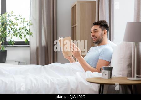 Mann lesen Buch im Bett zu Hause. Stockfoto