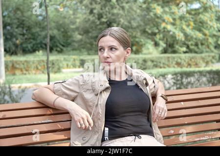 Blick der Frau mittleren Alters, die auf der Bank auf einer der Straßen der Stadt ruht. Stockfoto