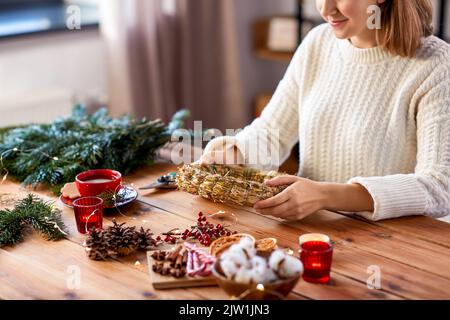 Frau macht tannenweihnachtskranz zu Hause Stockfoto