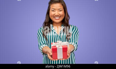 Glückliche Frau mit Geburtstagsgeschenk über violett Stockfoto