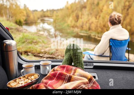 Blick auf den Fluss vom Auto aus mit Füßen unter der Decke Stockfoto