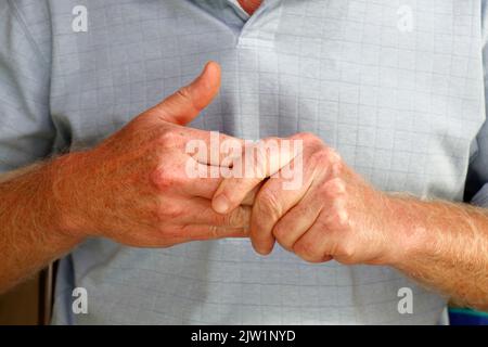 Nahaufnahme von reifen kaukasischen Männern mit der linken Hand, die die Finger seiner rechten Hand massieren, um Schmerzen und Schmerzen in Muskeln und Gelenken zu lindern. Stockfoto