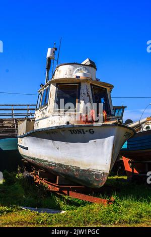 Ein alter Trawler im Trockendock in Nordkalifornien sitzt auf einem roten Anhänger gegen den blauen Himmel. Stockfoto