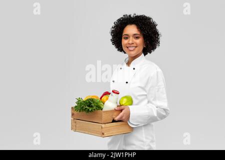 Glückliche lächelnde Köchin mit Essen in Holzkiste Stockfoto