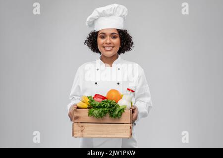 Glückliche lächelnde Köchin mit Essen in Holzkiste Stockfoto