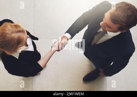 Ein weiterer erfolgreicher Deal: Zwei Geschäftsleute, die sich in einem Büro die Hände schütteln. Stockfoto