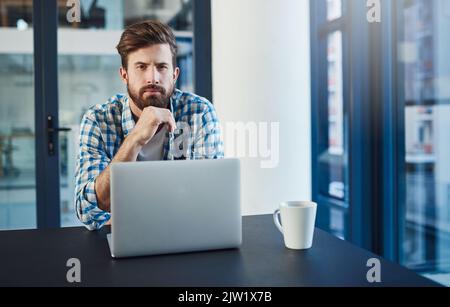 Arbeiten Sie, bis Sie sich nicht mehr vorstellen müssen. Porträt eines jungen Designers, der in einem modernen Büro an einem Laptop arbeitet. Stockfoto