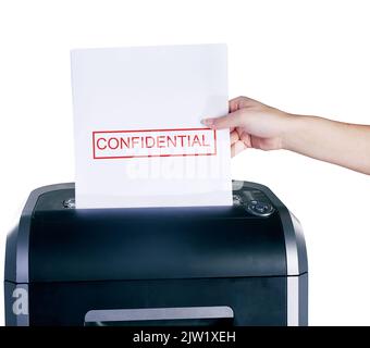 Die Beweise loswerden. Studioaufnahme einer Frauenhand, die ein vertrauliches Dokument vor weißem Hintergrund in einen Aktenvernichter legt. Stockfoto