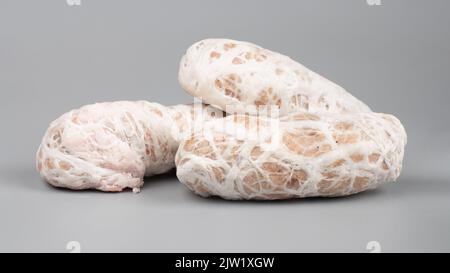 Rohe Hackfleischbällchen im Schweinedarm auf grauem Hintergrund. Stockfoto