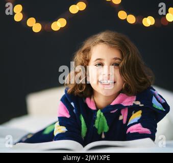 Ihr Lieblingsmärchen. Ein junges Mädchen liegt und liest im Bett. Stockfoto