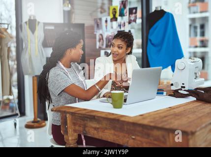 Zwei junge Modedesigner, die an einem Laptop arbeiten. Stockfoto