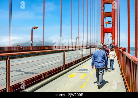 Fußgänger, die an einem warmen und sonnigen Tag den Bürgersteig entlang über die Golden Gate Bridge in San Francisco, Kalifornien, gehen. Stockfoto