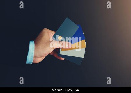 Abrechnung per Karte. Studioaufnahme eines nicht identifizierbaren Geschäftsmannes mit einer Auswahl von Kreditkarten vor schwarzem Hintergrund. Stockfoto