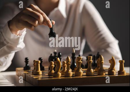 Gesichtslose kaukasische Frau im weißen Hemd, die Schach spielt. Stockfoto