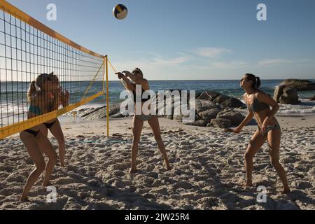 Volleyballspielerinnen spielen am Strand Stockfoto