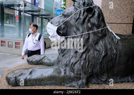 Tokio, Japan. 24. August 2022. Ein Mann mit Gesichtsmaske kommt am Samstag an einer Löwenstatue mit Gesichtsmaske vorbei, dem Maskottchen des Kaufhauses Mitsukoshi im Tokioter Ginza-Modeviertel. Kredit: SOPA Images Limited/Alamy Live Nachrichten Stockfoto