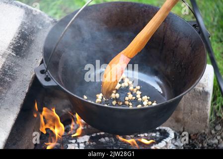 Großer Holzlöffel in einem Kessel auf Feuer Stockfoto