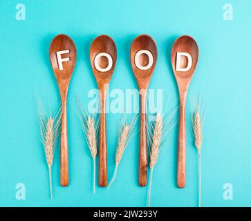 Holzlöffel mit dem Wort Lebensmittel- und Weizenohren, steigende Preise, Krise und Engpässe, Probleme in der Lieferkette Stockfoto